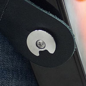 Może przedstawiać: Czarny skórzany pasek do gitary z srebrnym metalowym guzikiem. Pasek jest przymocowany do gitary.