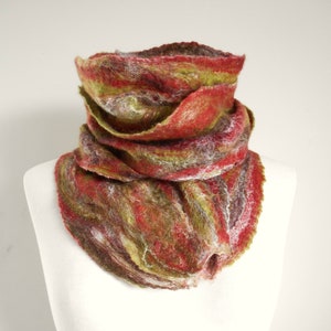 May include: A felted cowl scarf in red, green, brown, and white. The scarf is displayed on a white mannequin, highlighting its textured, layered design. The cowl is designed to be worn around the neck for warmth and style, a cosy accessory.