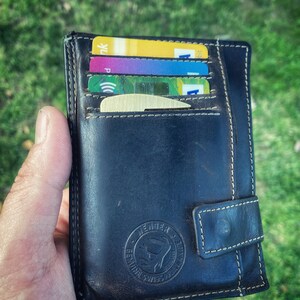 May include: A black leather wallet with a stitched flap and a gold embossed logo that says "Leather & Style". The wallet is open and has several credit cards inside.