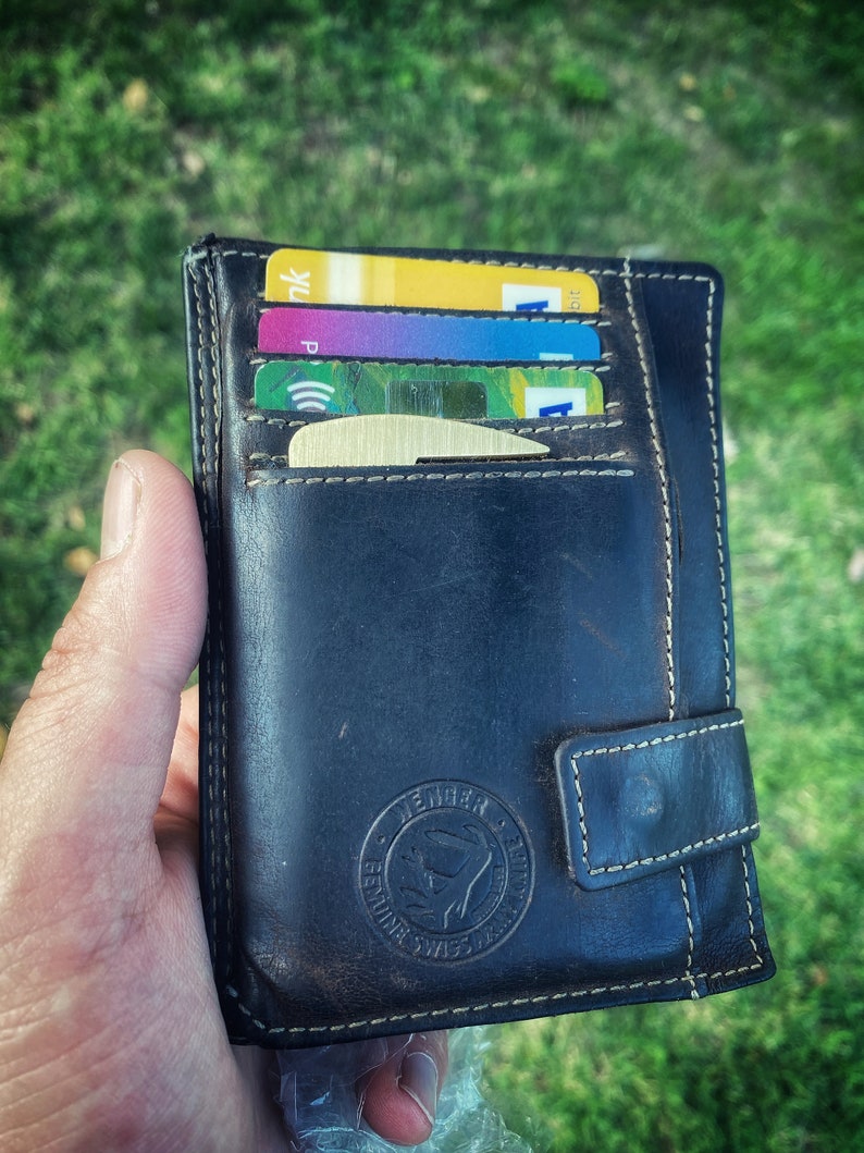 May include: A black leather wallet with a stitched flap and a gold embossed logo that says "Leather & Style". The wallet is open and has several credit cards inside.