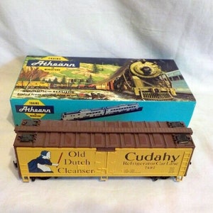May include: A brown and yellow model train boxcar with the words "Old Dutch Cleanser" and "Cudahy Refrigerator Car Line 7487" printed on the side. The boxcar is a model train made by Athearn.