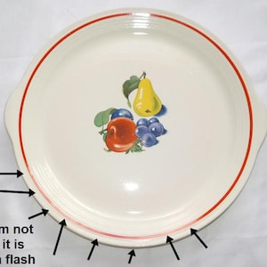 Può includere: Piatto da portata in ceramica bianco sporco con bordo rosso e illustrazione di frutta. L'illustrazione presenta una pera gialla, una mela rossa e uva blu. Il piatto ha due piccole maniglie.