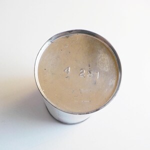 Puede incluir: La parte inferior de un recipiente de metal plateado con el n&uacute;mero "4231" impreso en la parte inferior.