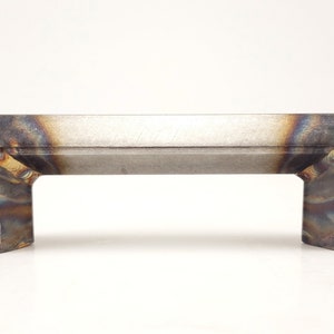 May include: A metal door handle with a rectangular shape and a brushed finish. The handle has a slightly curved design and is made of a durable metal.