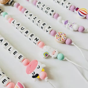 May include: A handmade wooden sign with the text "Welcome" in a handwritten style. The sign is painted white with a distressed finish and features a small, decorative heart. It is designed for indoor or outdoor use.