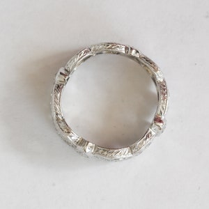 Pu&ograve; includere: Un anello a fascia d'argento con un design inciso dettagliato. L'anello ha una finitura liscia e lucida.