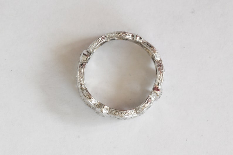 Pu&ograve; includere: Un anello a fascia d'argento con un design inciso dettagliato. L'anello ha una finitura liscia e lucida.
