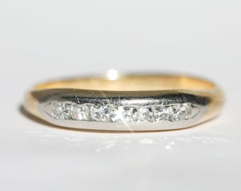 Puede incluir: Un anillo de banda de oro y plata con una fila de pequeños diamantes.