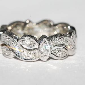Pu&ograve; includere: Un anello a fascia d'argento con un design delicato e intricato che presenta una fila di piccoli diamanti e un diamante pi&ugrave; grande di forma a marquise al centro.