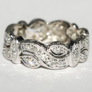 Pu&ograve; includere: Un anello a fascia d'argento con un design delicato e intricato che presenta una serie di piccoli diamanti incastonati in un motivo ondulato.