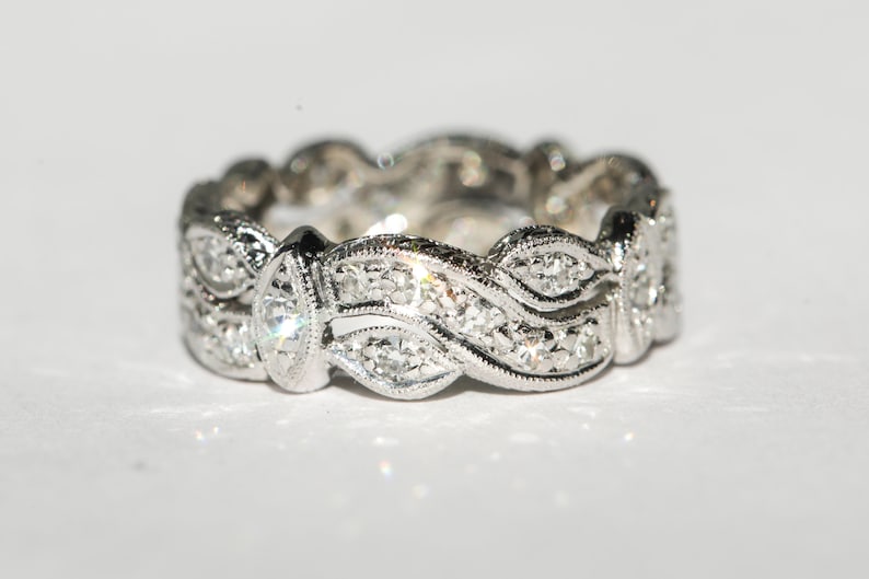 Pu&ograve; includere: Un anello a fascia d'argento con un design ondulato e piccoli diamanti incastonati nel metallo.