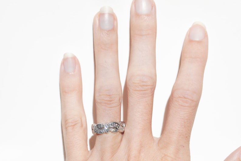 Pu&ograve; includere: Un anello d'argento con un delicato design di foglie e piccoli diamanti.