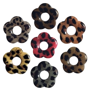 Puede incluir: Siete pinzas para el pelo con forma de flor con un diseño de estampado de leopardo. Las pinzas son de varios colores, incluyendo marrón, negro, rojo y verde.