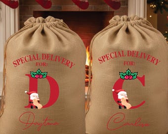 May include: Two burlap Christmas gift bags with drawstring closures. The bags have the text "SPECIAL DELIVERY FOR:" in red, with a large red letter and a Santa Claus graphic. One bag says "Daytona" and the other says "Carlisa".