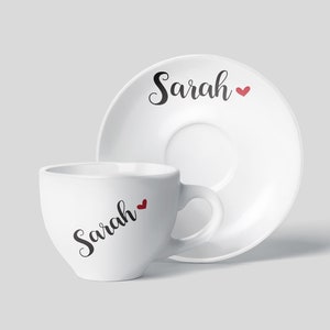 May include: White ceramic coffee cup and saucer set with the name "Sarah" and a small red heart printed on both pieces.