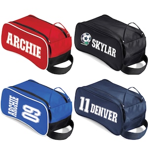 May include: Four personalised shoe bags in red, black, blue, and navy. Each bag features a white name or number, with a black handle and trim. The bags are designed for sports equipment.