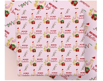 May include: Pink wrapping paper with a repeating pattern of a bunny wearing a Santa hat, a wrapped gift, and the name "Isabella" with "Merry Christmas" text. Green and red ribbon-like designs are also present.