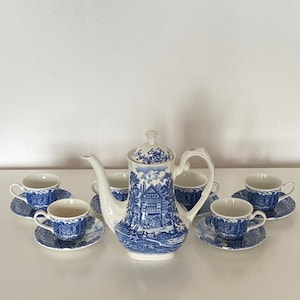 May include: A blue and white porcelain tea set with a teapot and four cups and saucers. The teapot and cups feature a blue and white floral design.