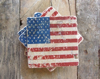May include: Set of four coasters featuring a distressed American flag design. The coasters are made of a light brown material with red, white, and blue paint.