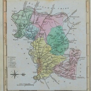 May include: A vintage map of Middlesex, England, with the city and county town highlighted in red. The map is divided into different colored sections, each representing a different hundred. The map includes the names of towns and villages, rivers, and other geographical features.