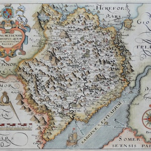 May include: An antique map of the county of Monmouthshire, Wales, with a compass rose and a scale bar. The map is hand-colored and shows the rivers, towns, and mountains of the region. The text on the map includes "Monumetiensis Comitatus, Quem Olim Incoluebant Silures", "Brecknok Pars", "Geanor", "Herefor Pars", "Gloces", "Tria Pars", "Sabrine Estuarium", "Somer: Seensis Pars", and "Bristol".