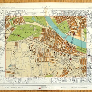 Op de afbeelding: Een vintage kaart van Londen, met gedetailleerde stratenplannen, parken en de rivier de Theems. De kaart is verdeeld in vierkanten van een halve mijl, met tekst die de titel en schaal van de kaart aangeeft. Het kleurenpalet omvat bruin, groen en blauw.