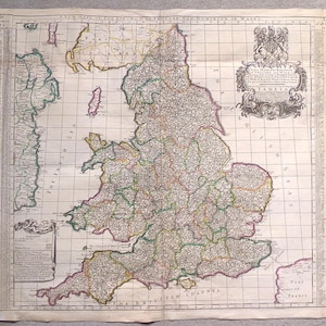 Op de afbeelding: Een antieke gegraveerde kaart van het Koninkrijk Engeland en het Vorstendom Wales, voorzien van een centraal raster, een decoratieve cartouche en alfabetische tabellen van steden aan de linker- en rechterkant, op verouderd papier.