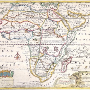 Op de afbeelding: Antieke kaart van Afrika, met gedetailleerde geografische informatie. De kaart is met de hand getekend met ingewikkelde details, waaronder tekstlabels, kompasrozen en decoratieve elementen. De kaart is gekleurd met een palet van geel, blauw en rood en is omlijst met een decoratieve rand.