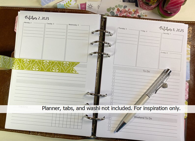 May include: A weekly planner with a green and white washi tape on the left side and a silver pen on the right side. The planner is open to the week of October 2nd and 8th, 2023. The text "Planner, tabs, and washi not included. For inspiration only." is printed at the bottom of the page.
