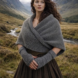 May include: A woman wearing a gray knitted shawl and matching fingerless gloves, paired with a long brown skirt. The scene is set in a mountainous landscape with a river, under an overcast sky. The clothing appears warm and suitable for cooler weather.