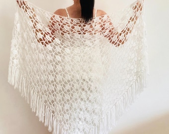Könnte beinhalten: Ein weißer Häkelschal mit Fransen. Der Schal wird offen präsentiert und zeigt das detaillierte, blumenartige Design. Dieses zarte, handgefertigte Accessoire ist ein schönes Kleidungsstück.