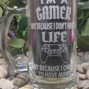 May include: A clear glass beer stein with a white etched design that reads "I'm a gamer not because I don't have a life but because I choose to have many". The design also includes a video game controller.
