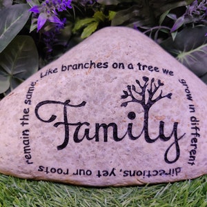 May include: A light brown stone with the word "Family" written in black cursive lettering. The stone also has a tree design and the text "remain the same. Like branches on a tree we grow in different directions, yet our roots"