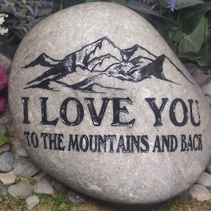 May include: A gray stone with a black mountain range design and the text "I love you to the mountains and back".