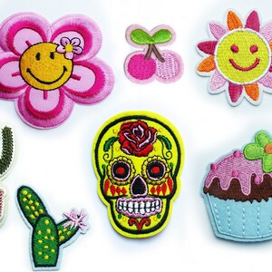 Peut inclure: Ensemble de 10 patchs brodés colorés à repasser, présentant une variété de motifs, notamment une fleur souriante, une cerise, un soleil souriant, un crâne rose avec une rose, un crâne jaune avec une rose, un cupcake avec un glaçage rose, un cupcake avec un glaçage violet, un cactus en pot et deux cactus.