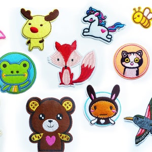 Peut inclure: Un ensemble de 10 patchs brodés colorés à repasser représentant différents animaux, dont un flamant rose, un renne jaune, une licorne blanche, un renard roux, une grenouille verte, un ours brun, un lapin brun, un chat, une abeille et un colibri.