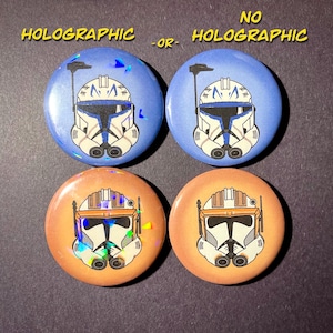 May include: Four round buttons with images of Star Wars clone trooper helmets. Two buttons are blue with a white helmet and two buttons are orange with a white helmet. The top two buttons have a holographic finish, while the bottom two buttons do not.