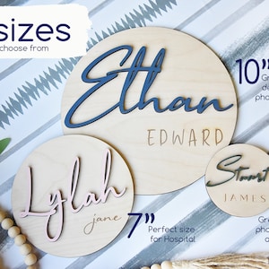 K&ouml;nnte beinhalten: Drei Holz Kreise mit Namen in Kursivschrift. Die Kreise haben einen Durchmesser von 10 Zoll, 7 Zoll und 4 Zoll. Die Namen sind Ethan Edward, Lylah Jane und Stuart James.
