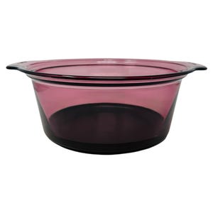 May include: A round, transparent, purple glass bowl with two small handles on either side. The bowl has a dark purple base and a lighter purple upper section. The bowl is empty and sits against a white background.
