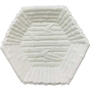May include: A white, hexagonal serving dish with a bamboo design. The dish features raised bamboo stalks and leaves, creating a textured surface. The edges are lined with bamboo-like detailing. This decorative dish is ideal for serving snacks or displaying decorative items.