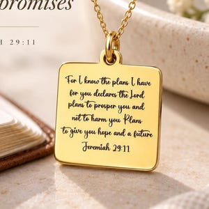 May include: A gold-toned square pendant necklace featuring the engraved text of Jeremiah 29:11. The pendant hangs from a delicate gold chain. The text reads: For I know the plans I have for you declares the Lord plans to prosper you and not to harm you Plans to give you hope and a future Jeremiah 29:11.
