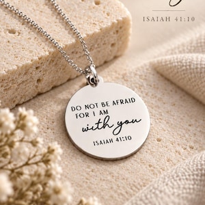 May include: A silver-toned circular pendant necklace featuring the engraved text "DO NOT BE AFRAID FOR I AM with you ISAIAH 41:10". The pendant hangs from a delicate silver-toned chain, with the same text printed in the background.