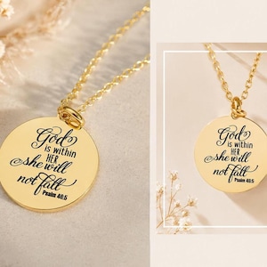 Op de afbeelding: Een goudkleurige ronde hanger aan een fijne ketting met de gegraveerde tekst: God is within her she will not fall Psalm 46:5. De hanger heeft een gepolijst, reflecterend oppervlak met zwarte letters.