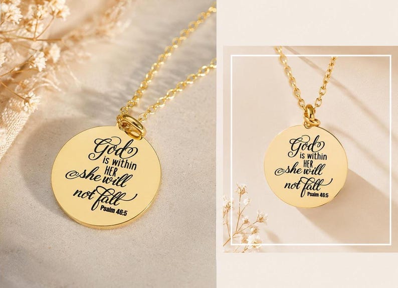 Op de afbeelding: Een goudkleurige ronde hanger aan een fijne ketting met de gegraveerde tekst: God is within her she will not fall Psalm 46:5. De hanger heeft een gepolijst, reflecterend oppervlak met zwarte letters.