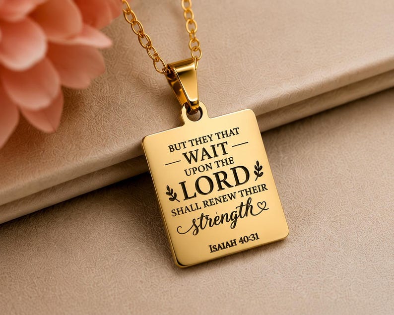 Op de afbeelding: Een goudkleurige rechthoekige hanger aan een bijpassende ketting met de gegraveerde zwarte tekst: BUT THEY THAT WAIT UPON THE LORD SHALL RENEW THEIR STRENGTH ISAIAH 40:31, versierd met kleine bladmotieven en een hartsymbool.