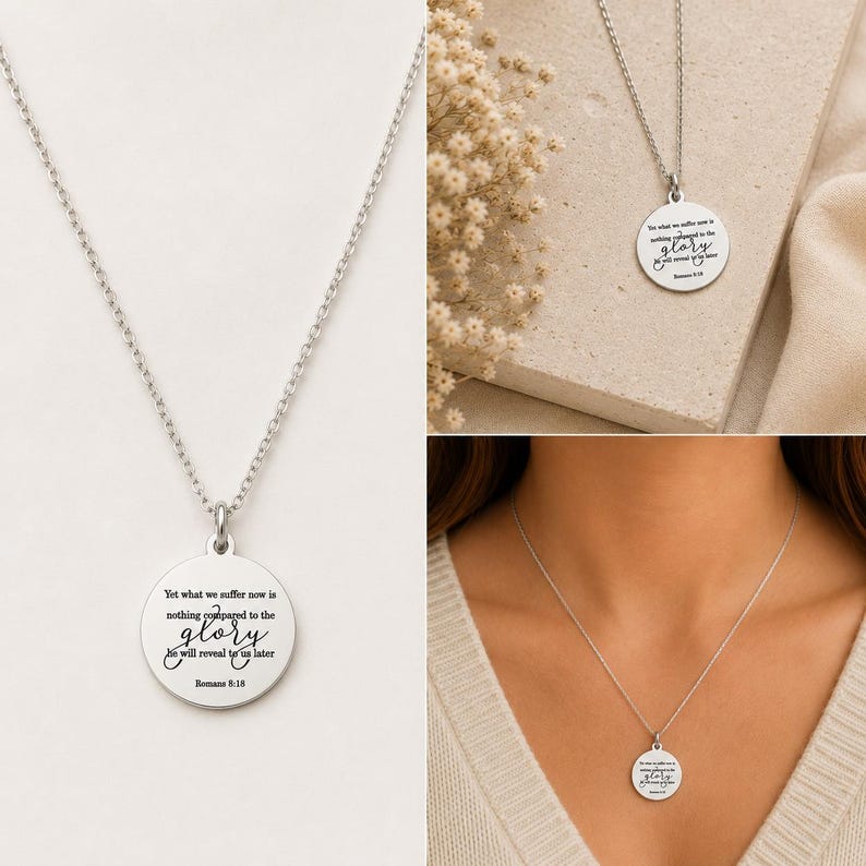 May include: A silver-toned circular pendant necklace featuring a delicate chain and a round metal charm engraved with the text: Yet what we suffer now is nothing compared to the glory he will reveal to us later Romans 8:18 in black lettering.