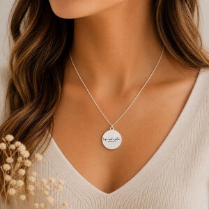 May include: A silver necklace with a circular pendant. The pendant has the words "Hope and a future" in a handwritten font. The necklace is worn on a person wearing a light-colored sweater.