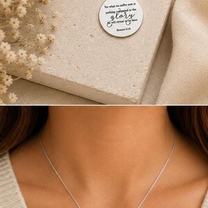 May include: A silver-toned circular pendant necklace featuring the engraved text: Yet what we suffer now is nothing compared to the glory that will reveal to us later Romans 8:18. The pendant hangs from a delicate matching silver-toned chain.
