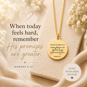 May include: A gold-toned circular pendant necklace featuring the engraved text 'Yet what we suffer now is nothing compared to the glory he will reveal to us later' and 'Romans 8:18'. The pendant hangs from a delicate gold-toned chain.