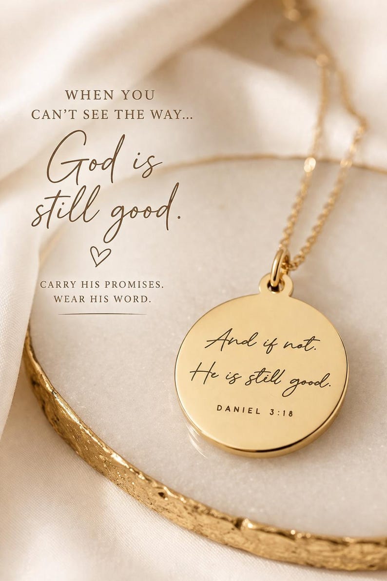 Op de afbeelding: Een goudkleurige ronde hanger aan een ketting met de gravure 'And if not. He is still good. DANIEL 3:18'. De hanger hangt aan een fijne gouden ketting. De tekst 'WHEN YOU CAN'T SEE THE WAY... God is still good. CARRY HIS PROMISES. WEAR HIS WORD.' is zichtbaar.